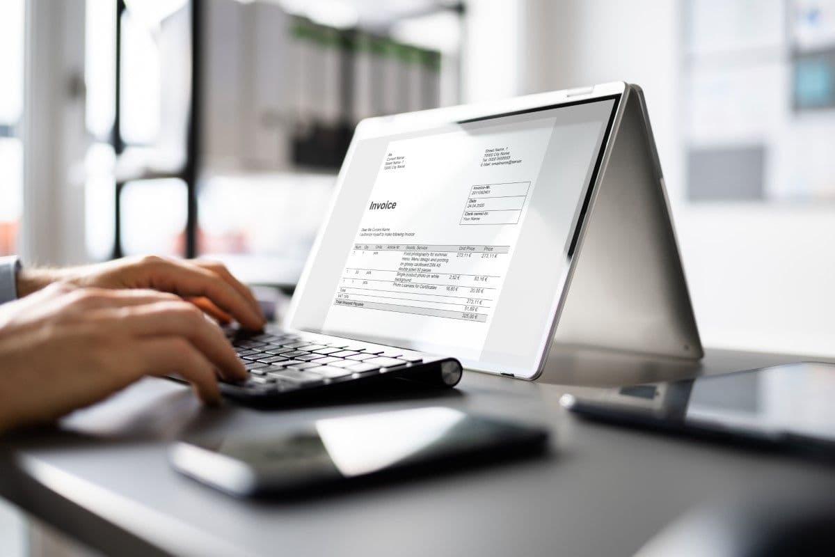 Hand using a tablet and keyboard to view an Invoice